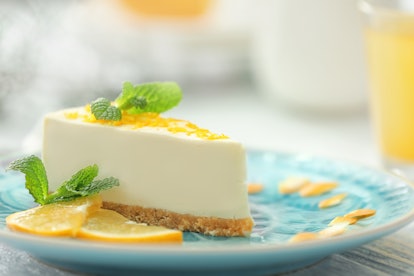 Tasty cheesecake slice with lemons on plate