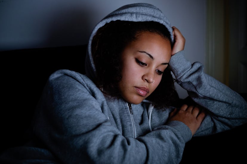 Sad woman lying on the couch at night