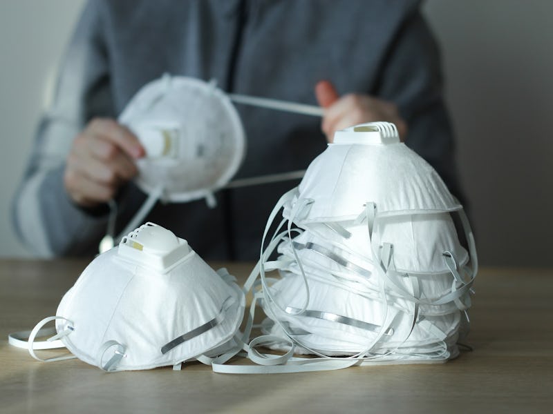 Coronavirus panic concept. Dust respirator masks on the table and a person in blurred background. N9...