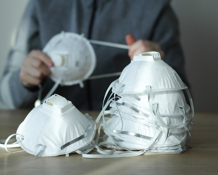 Coronavirus panic concept. Dust respirator masks on the table and a person in blurred background. N9...