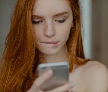 Closeup portrait of a beautiful redhead woman using smartphone 