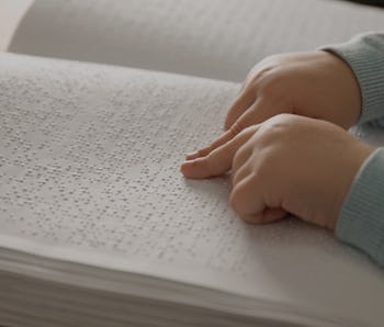 Blind child reading book written in Braille, closeup