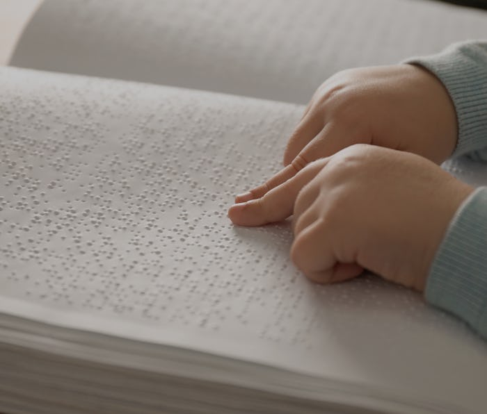 Blind child reading book written in Braille, closeup