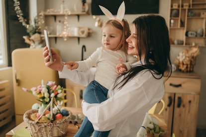 A woman holds her daughter while taking a selfie in the kitchen on Easter Sunday.