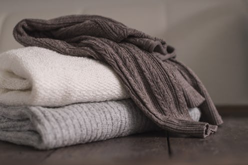 Stack of neatly folded woolen knitwear. Minimal lifestyle, capsule wardrobe. Autumn-winter men fashi...