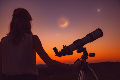 Girl looking at lunar eclipse through a telescope. My astronomy work.