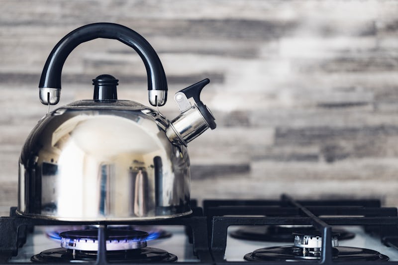 A metal silver teapot on a gas stove in the kitchen