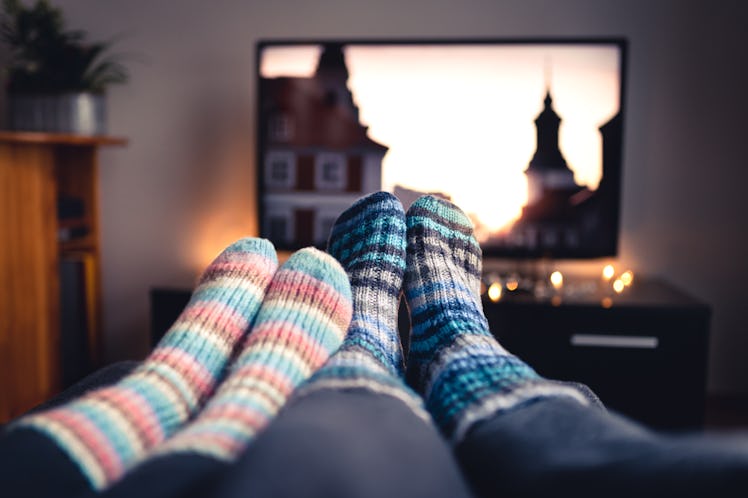 Couple with socks and woolen stockings watching movies or series on tv in winter.