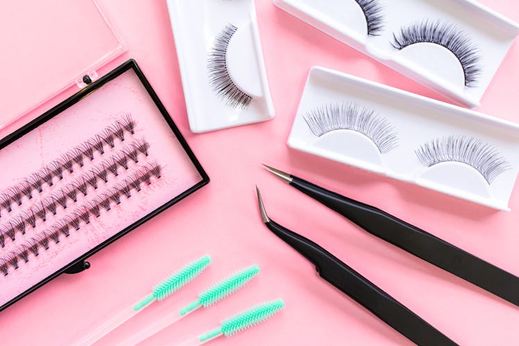 Tools for eyelash extension on trendy pastel pink background. False eyelashes, tweezers and brushes....