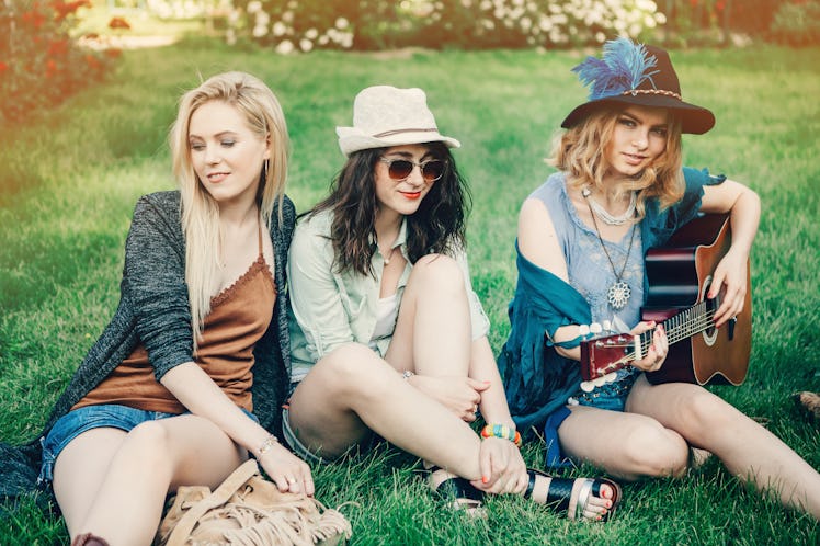 Summer holidays, vacation, travel and people concept - smiling young hippie women with guitar playin...