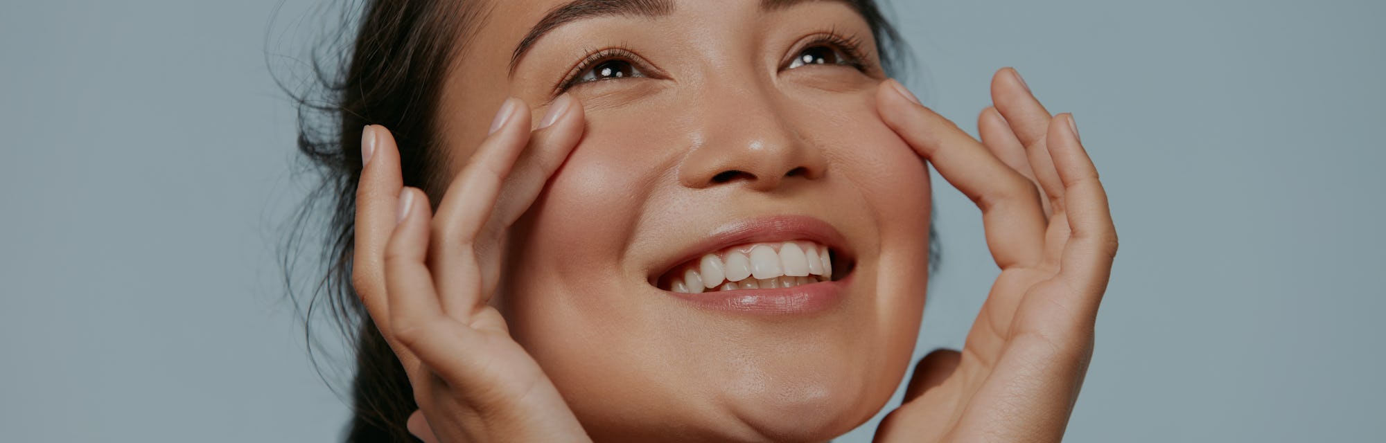 Skin care. Woman with beauty face touching healthy facial skin portrait. Beautiful smiling asian gir...