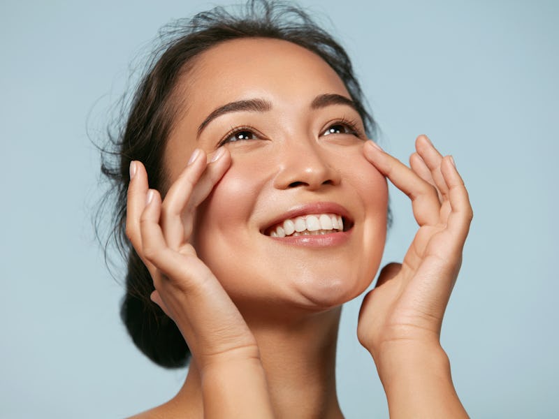 Skin care. Woman with beauty face touching healthy facial skin portrait. Beautiful smiling asian gir...