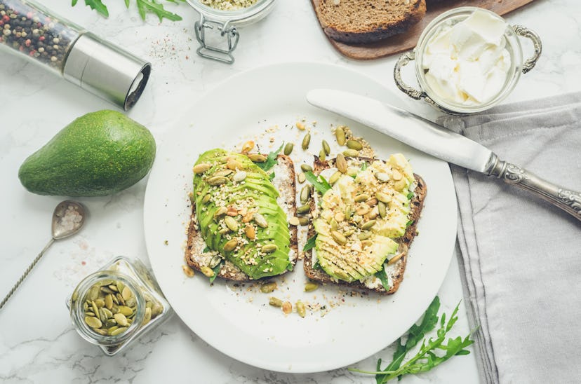 Healthy avocado toasts for breakfast or lunch with rye bread, cream cheese, arugula, sliced avocado,...