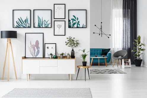 White living room interior with botanical posters on the wall and sofa in the background