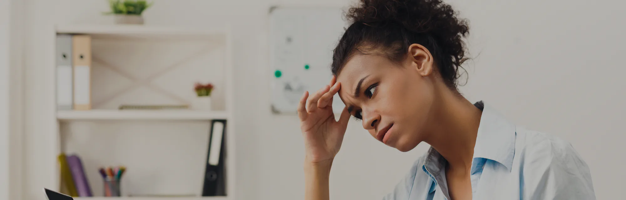 Deadline stress concept - sad african-american business woman sitting at desktop in office, working ...