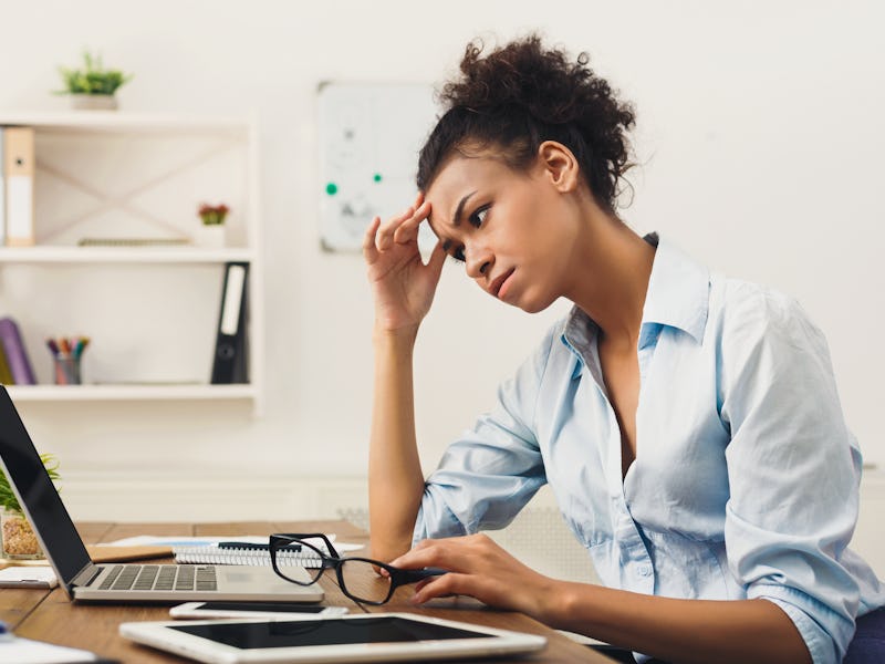 Deadline stress concept - sad african-american business woman sitting at desktop in office, working ...