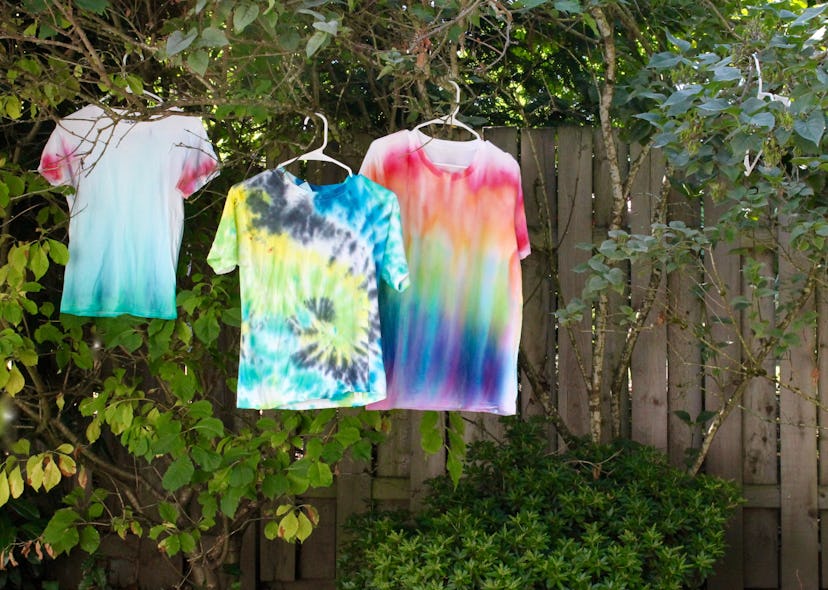 tie dye shirts hanging on lilac bush to dry