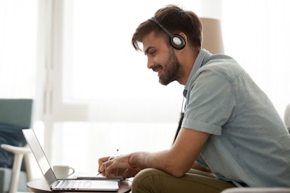 Happy man wearing headset study online learning foreign english language or watch webinar make notes...