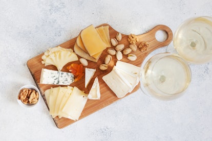 Cheese plate served with white wine, crackers and nuts, Top view. Assorted cheeses Camembert, Brie, ...