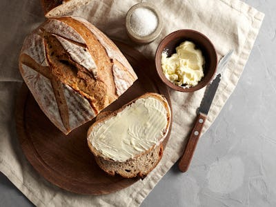 Artisan sliced toast bread with butter and sugar on wooden cutting board. Simple breakfast on grey c...