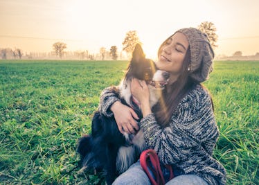 Young beautiful girl stroking her dog in a park at sunset - Asian woman playing with her dog
