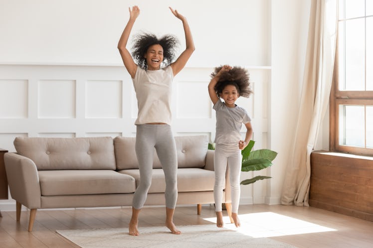 A happy woman dances with her niece in a bright living room.