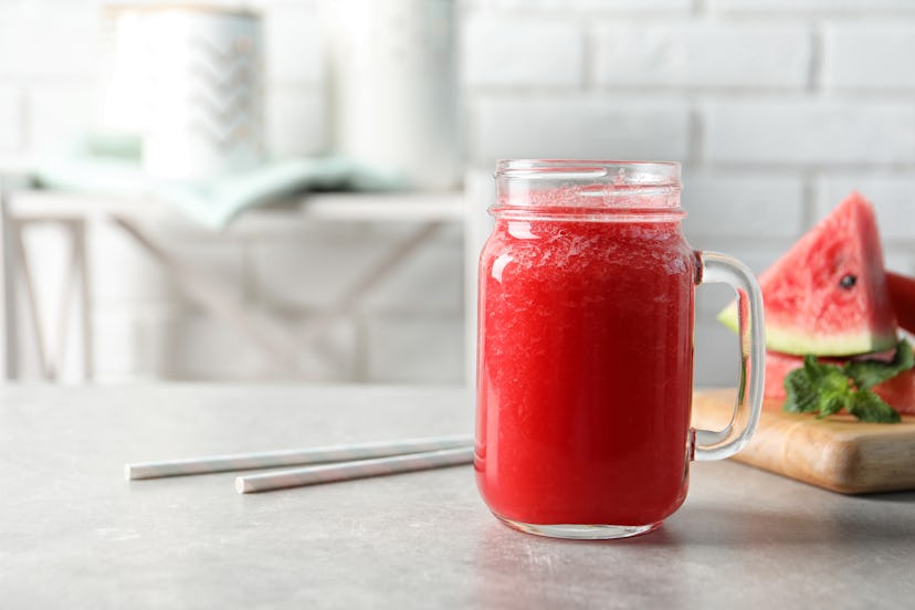 Tasty summer watermelon drink in mason jar on table against blurred background. Space for text