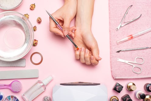 Nail care. beautiful women hands making nails painted with pink gentle nail polish on a pink backgro...