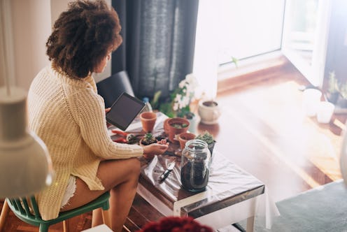 woman gardening while using tablet and sitting at home.