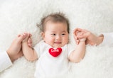 smiling baby on white rug, holding hands with parents, short middle names for baby girls