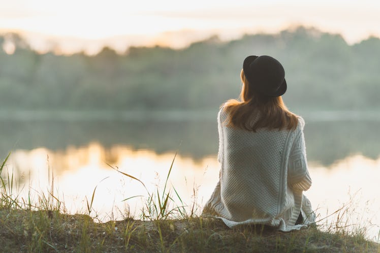 A girl sitting on the river bank in silence
