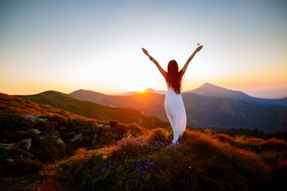Hiker woman standing with hands up achieving the top. Girl welcomes a sun. Conceptual design. Succes...