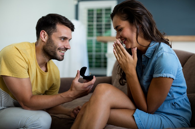 Man offering a engagement ring to woman in the living room at home