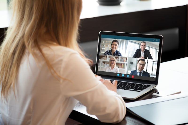 Back view of businesswoman speak using Webcam conference on laptop with diverse colleagues, female e...