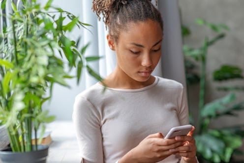 Woman holding a mobile phone looking at the screen and typing . - Image