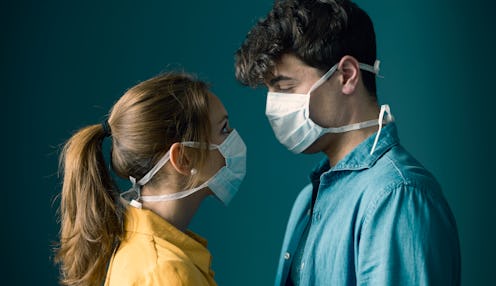 Young romantic loving couple wearing a protective face mask and staring at each other's eyes, pandem...