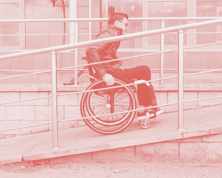 Man in a wheelchair use a wheelchair ramp.