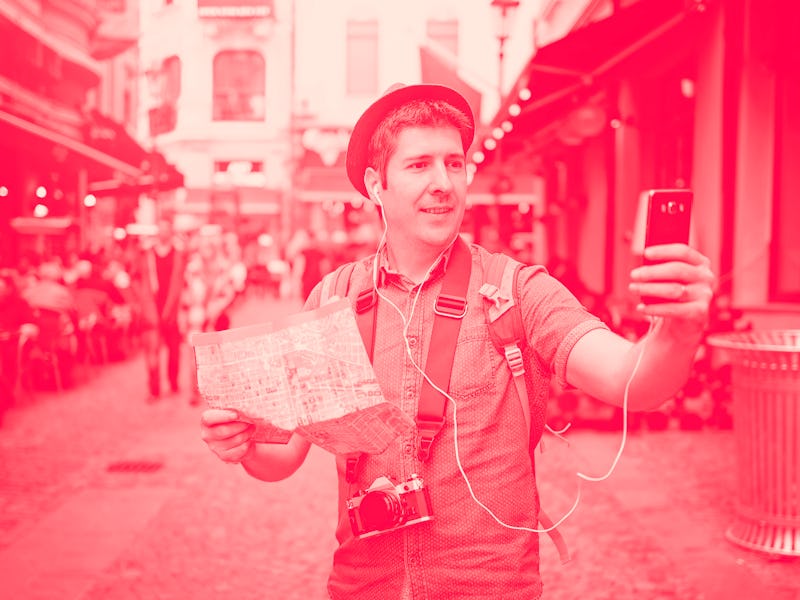 Travel Europe. Backpacker Traveler Man traveling alone on crowded streets in old town. Neck camera a...