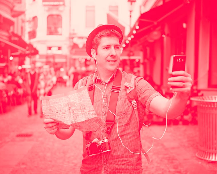 Travel Europe. Backpacker Traveler Man traveling alone on crowded streets in old town. Neck camera a...