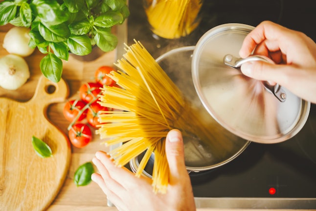Process of cooking homemade italian pasta. Lifestyle background. Man droping spaghetti into boiling water. Closeup. Horizontal. 