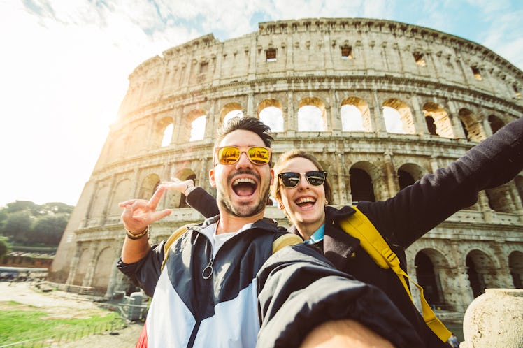 A happy couple snaps a selfie in front of the Colosseum in Rome. 