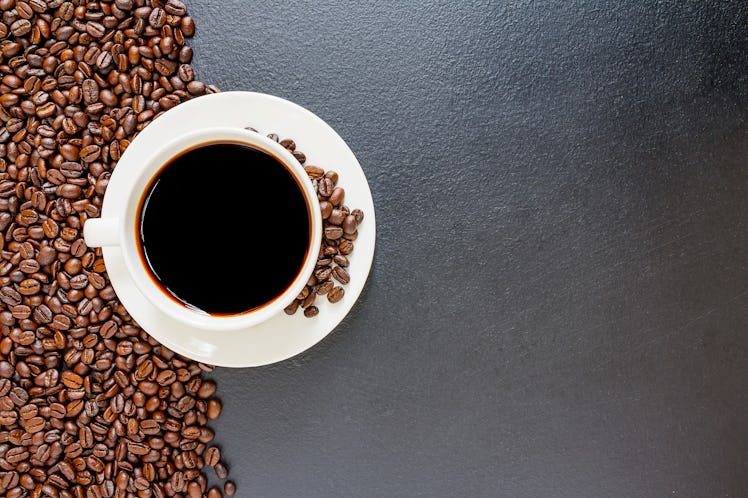 Black coffee in a cup of coffee and coffee beans placed on the old table Top view with empty space f...