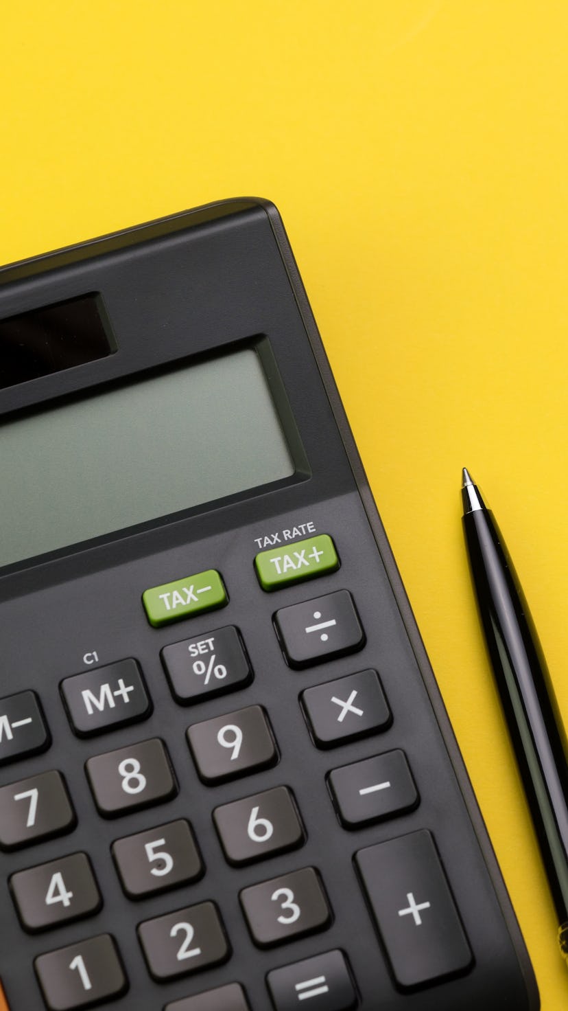 Flat lay or top view of black pen with calculator on vivid yellow background table with blank copy s...