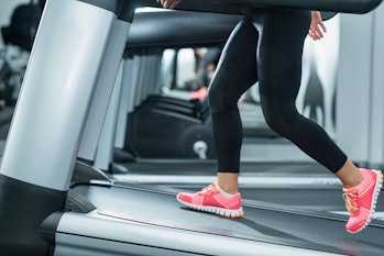 Woman using incline threadmill in modern gym. Incline threadmills are used to simulate uphill walkin...