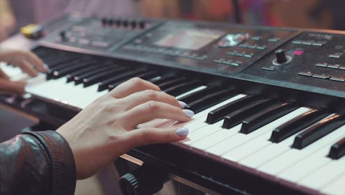 MIDI keyboard synthesizer piano keys. Stock. Woman playing the synthesizer. A music instrument backg...
