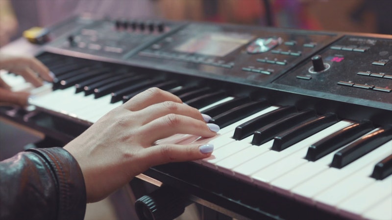MIDI keyboard synthesizer piano keys. Stock. Woman playing the synthesizer. A music instrument backg...