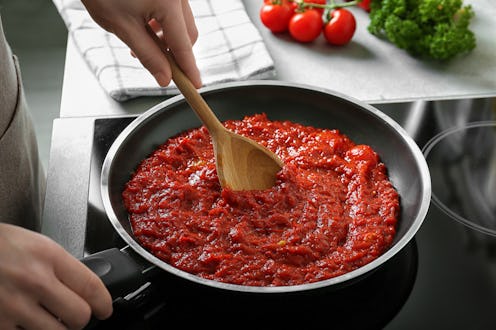 Woman preparing tomato sauce in frying pan