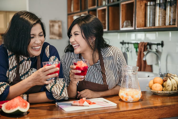 A happy mother and daughter share some cocktails together at home. 