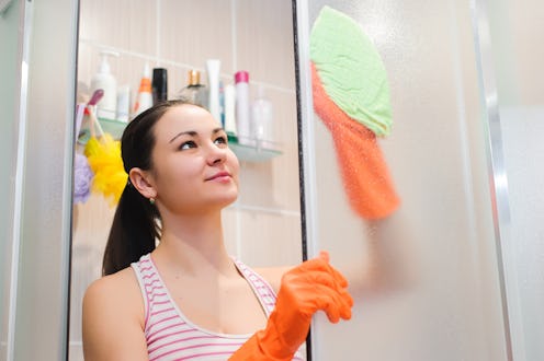 portrait of young woman cleaning shower door