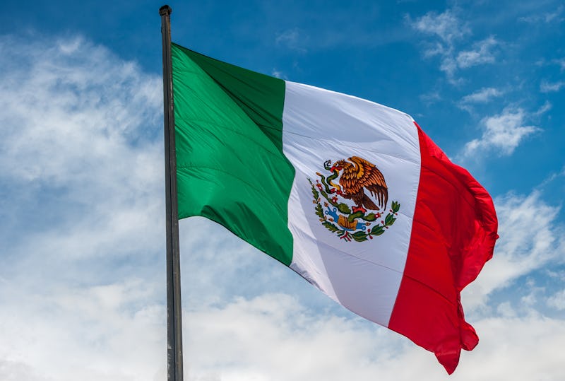 Flag of Mexico over blue cloudy sky